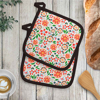 Floral patterned pot holder on a wooden surface with bread and coffee.