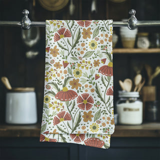 Tea towel with hand drawn illustration of flowers and ladybugs hanging on a rack sold at Jean C studio