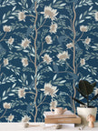 Image of wallpaper on a wall featuring stylized white and tan flowers, bluebirds and light greenish blue leaves against a medium dark teal background
