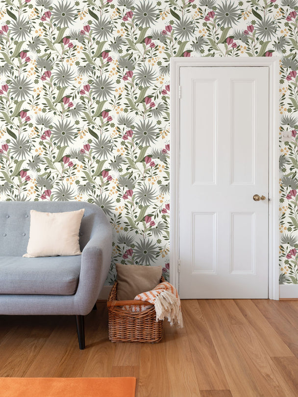 Image of wallpaper on a living room wall featuring silver colored zinnias pink tulips with a lot of green and gold leaves against a white background