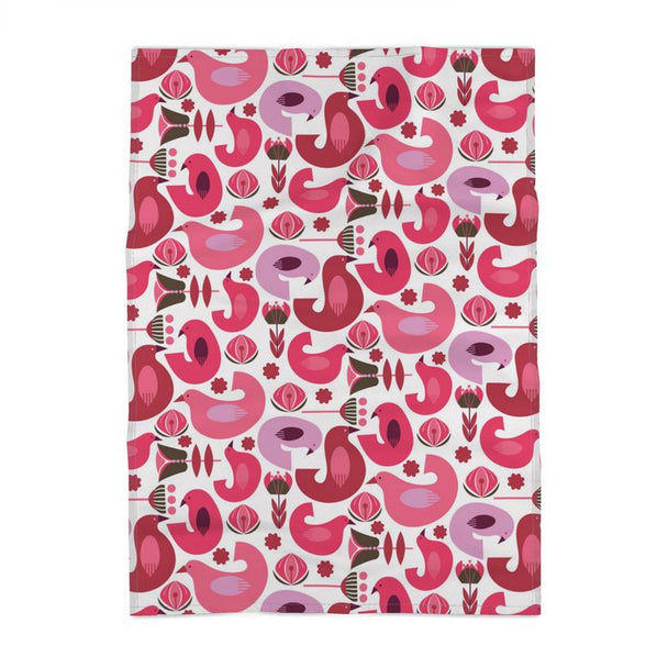 image of a cotton tea towel with many stylized birds in different orientations in a color palette of pinks and corals. There are also flowers among the birds in the same color palette. They resemble tulips. The background is a pale cream.