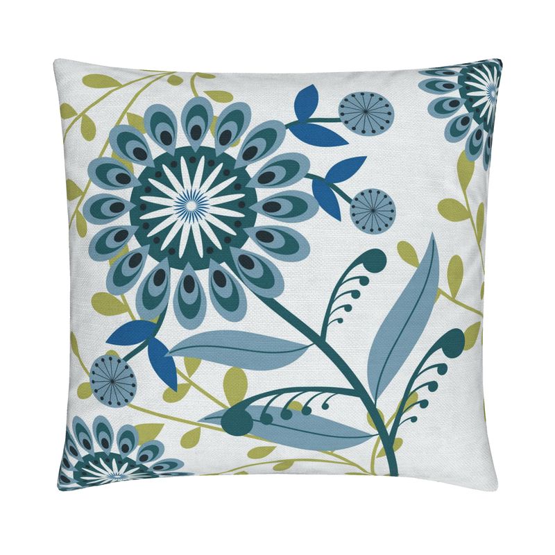 closeup image of a throw pillow. the pillow has several flowers in a palette of medium and light blue green and cream with stylized petals. There are other abstract small blue flowers surrounding it. There are also yellow green leaves in the background. The background is a very pale cream color.