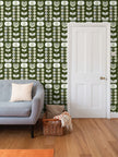 image of wallpaper on a living room wall featuring stylized large pale  green retro style flowers and light green and blue leaves against a medium warm green  background