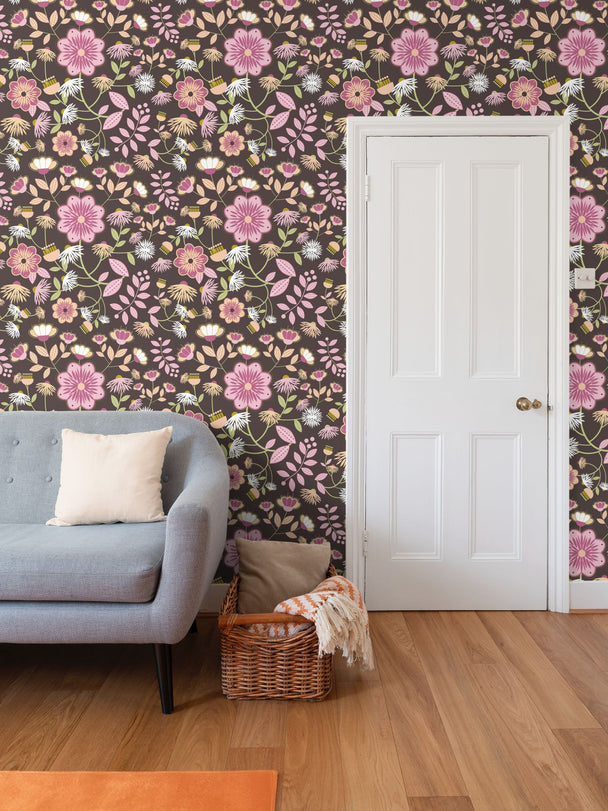 image of wallpaper on a living room wall featuring stylized large pale  pink and rose flowers and light green and peach colored leaves against a medium warm brown  background