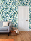 image of wallpaper on a living room wall featuring stylized tall teal and blue asters on green stems against a pale cream background