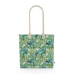 Image of tote bag with blue flowers with orange centers, white flowers, and pale green leaves against a medium green background.