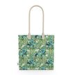Image of tote bag with blue flowers with orange centers, white flowers, and pale green leaves against a medium green background.