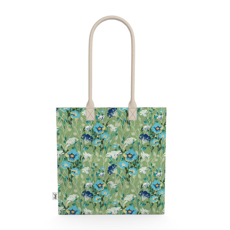 Image of tote bag with blue flowers with orange centers, white flowers, and pale green leaves against a medium green background.