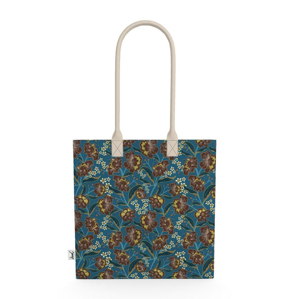 Image of tote bag with bold cocoa and gold colored flowers, teal and gold leaves, gold berries against a medium blue background.