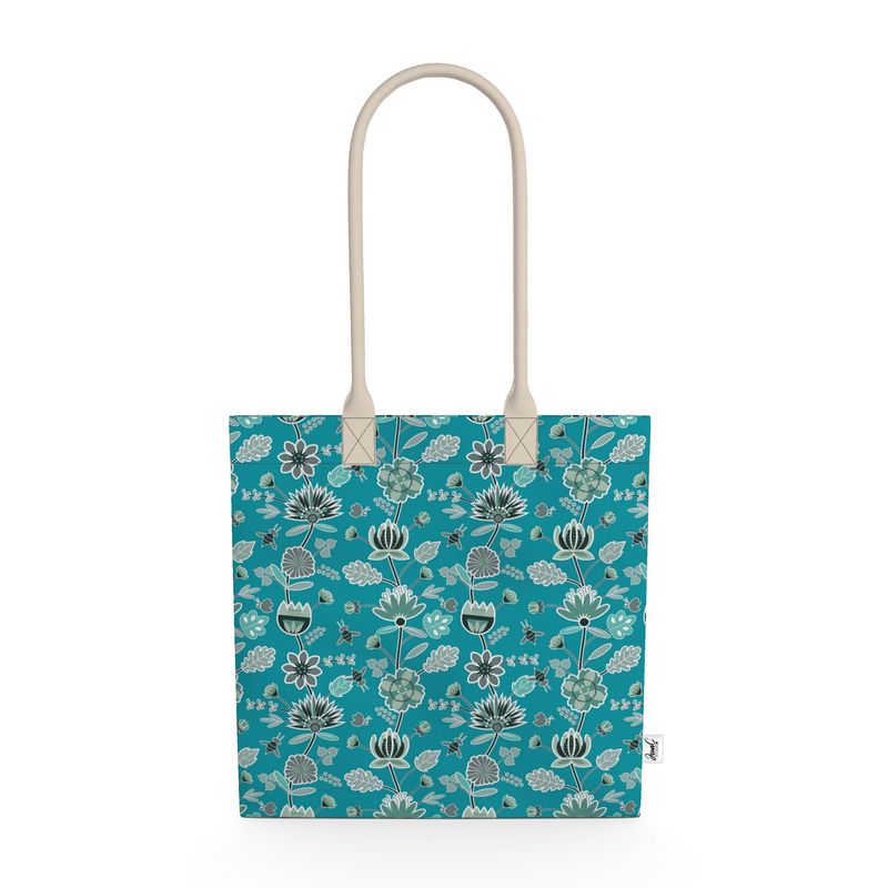 Image of tote bag with abstract flowers in blue, blue green and silver against a medium blue background. Also visible are bees and butterflies.
