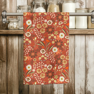 Floral Autumn patterned towel hanging on a wooden rack with jars in the background