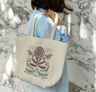 Person holding a tote bag with illustration of moths and big flower 