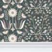 Image of wallpaper closeup featuring stylized large pale  flowers and light tan leaves and pinkish birds against a medium slate green  background