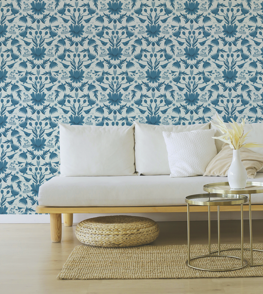 Image of wallpaper on a living room wall featuring stylized large teal colored flowers and birds against a pale blue  background